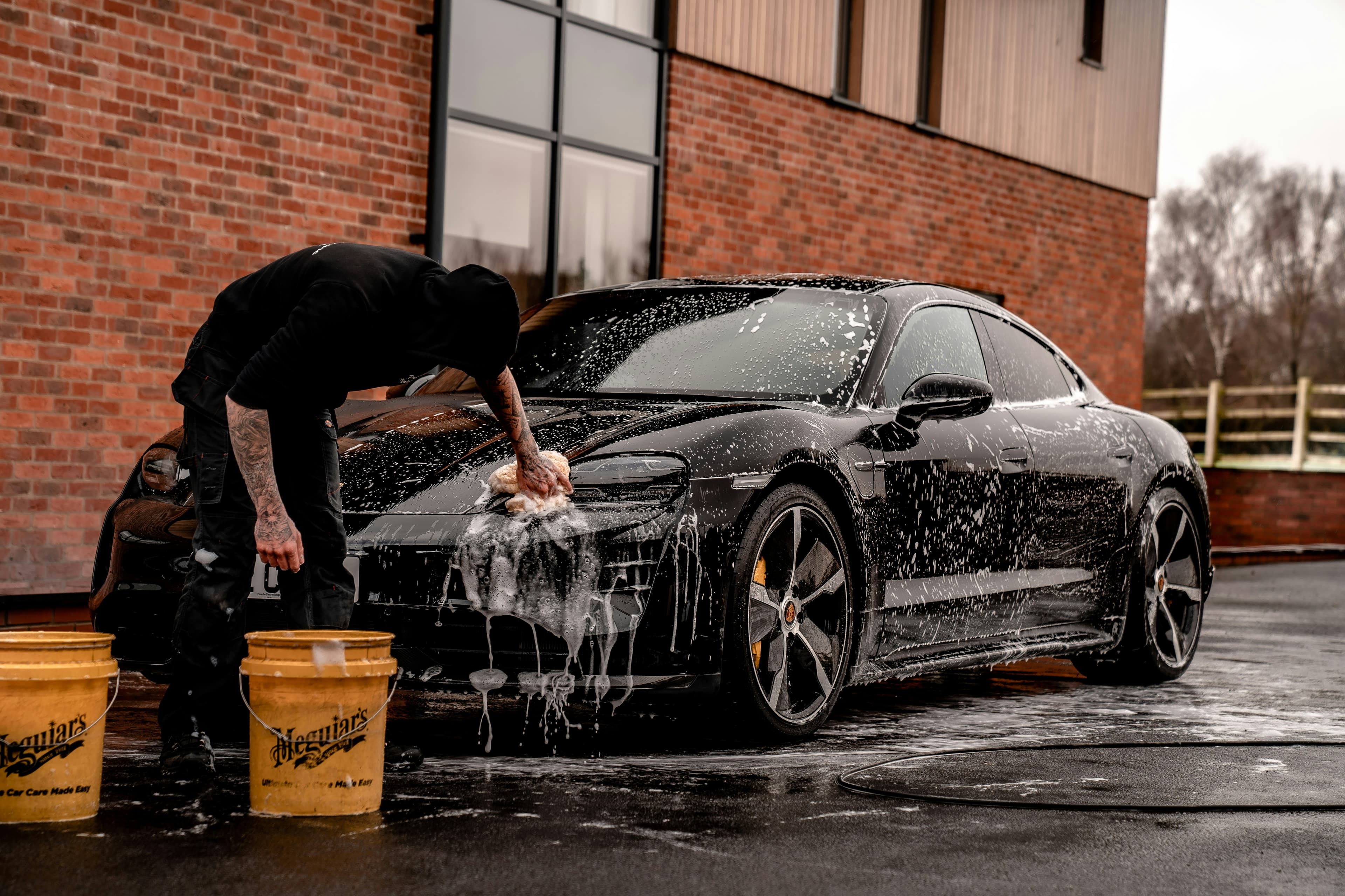 Hand wash mitt scrubbing car panel with thick soap foam