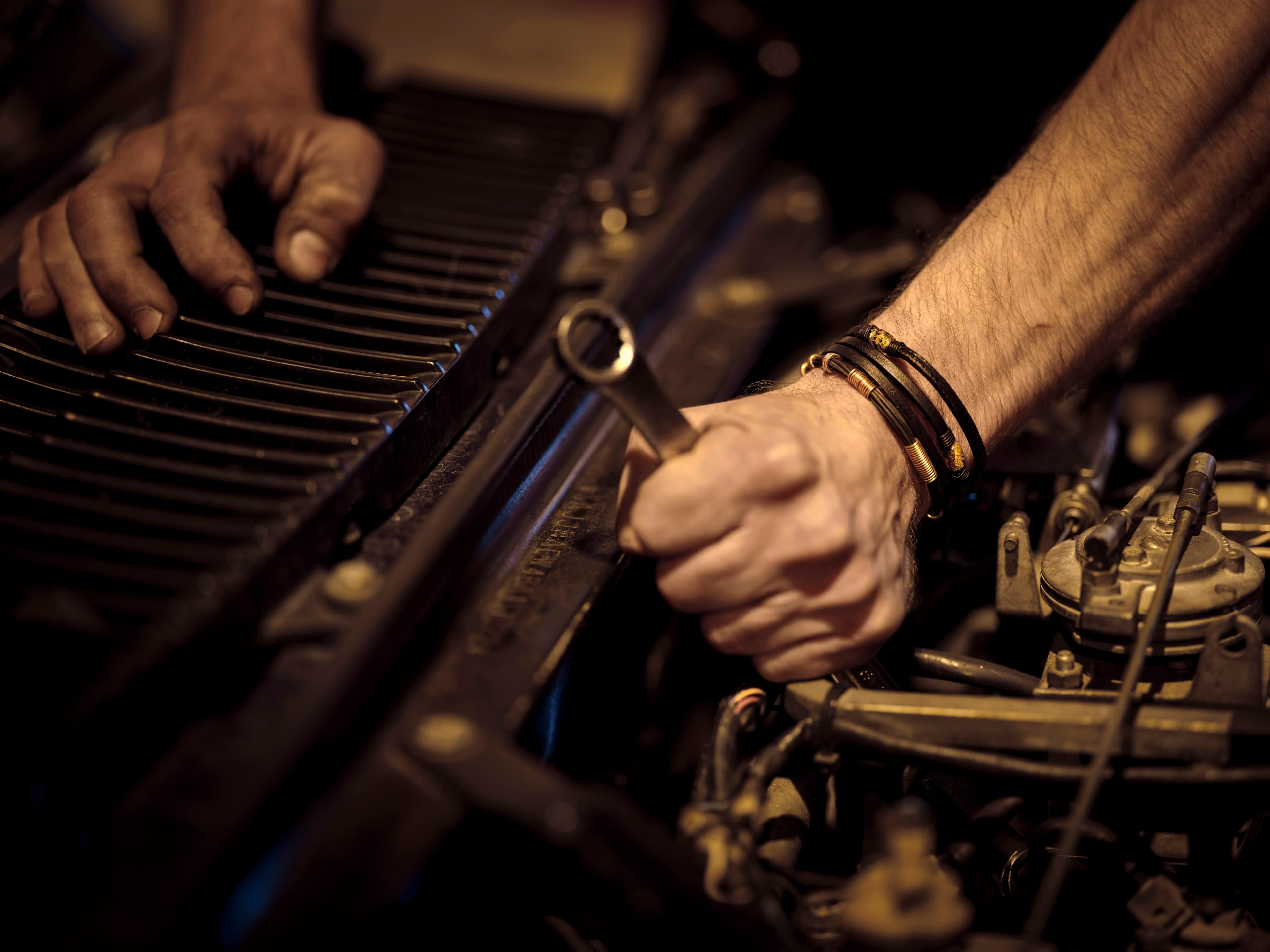 Mechanic technician working on car components under open hood